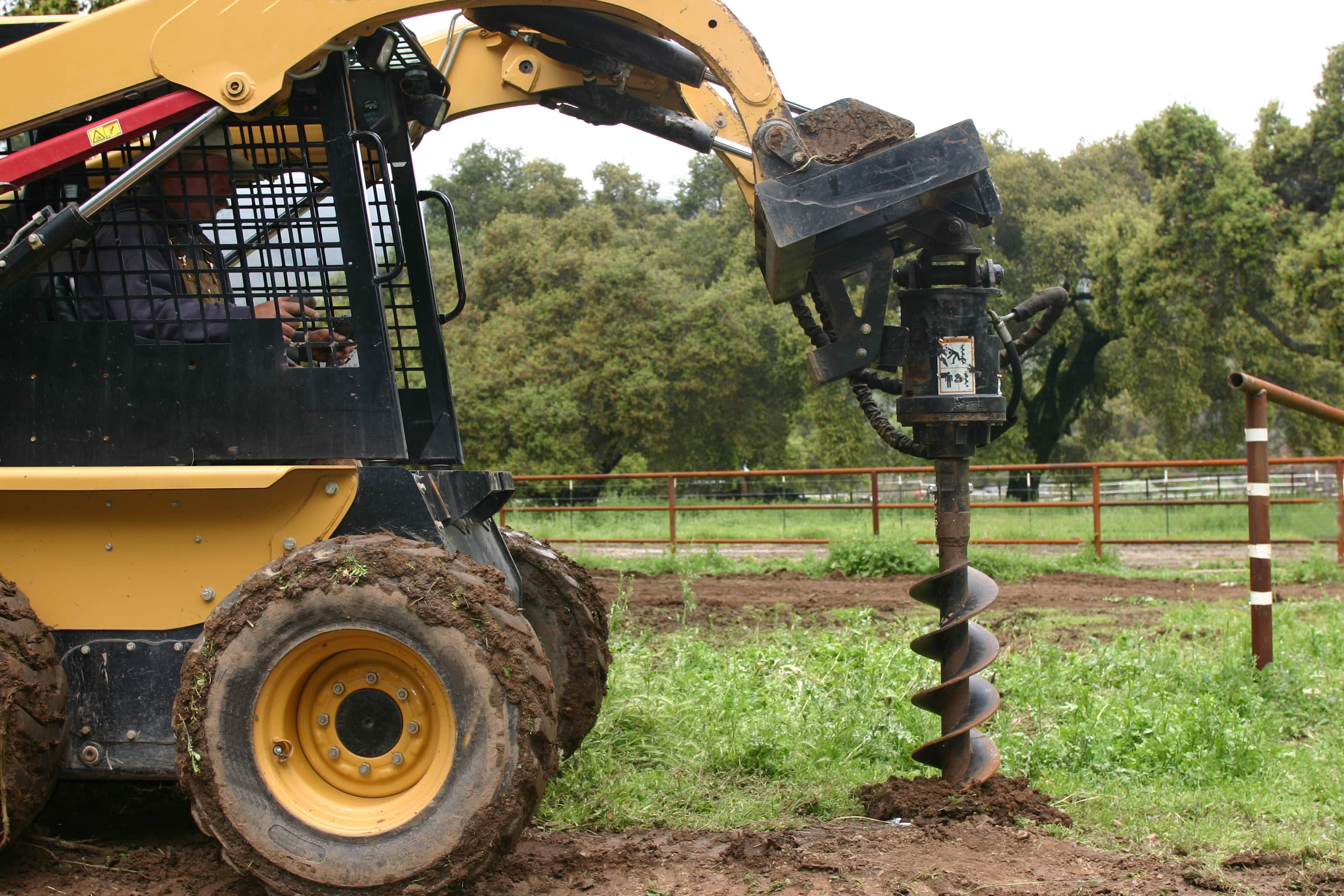 skid steer with auger attachment digging hole